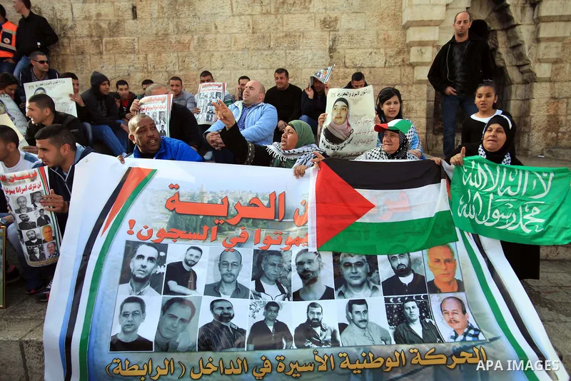 Palestinian protesters hold posters and banners with portraits of Palestinian prisoners in Israeli jail on March 8, 2014 during a demonstration to called for their release at the Damascus Gate in Jerusalem's Old City. Ph...
