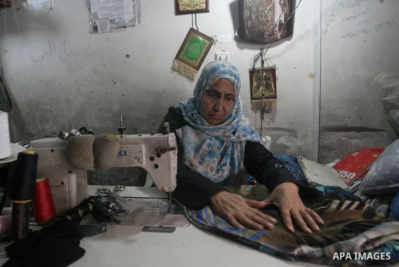 Samah Qeshta, 47, A Palestinian tailor sews at her workshop in Rafah southern in Gaza Strip on March 8, 2014. Samah, is a widow working to help her sons. On March 8 people around the globe celebrate International Women's...