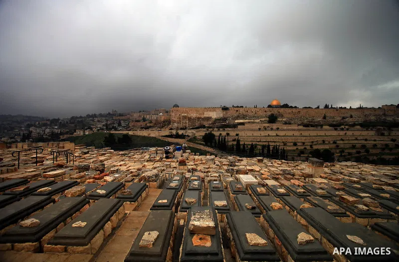 An Ultra-Orthodox Jewish man walks at the Jews cemetery in Ras al-Amud during a hazy and cloudy weather, in Jerusalem's Old City March 09, 2014, The Dome of the Rock mosque is seen in the background. Photo by Saeed Qaq