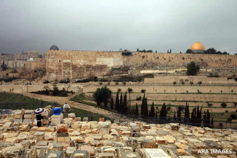 An Ultra-Orthodox Jewish man walks at the Jews cemetery in Ras al-Amud during a hazy and cloudy weather, in Jerusalem's Old City March 09, 2014, The Dome of the Rock mosque is seen in the background. Photo by Saeed Qaq