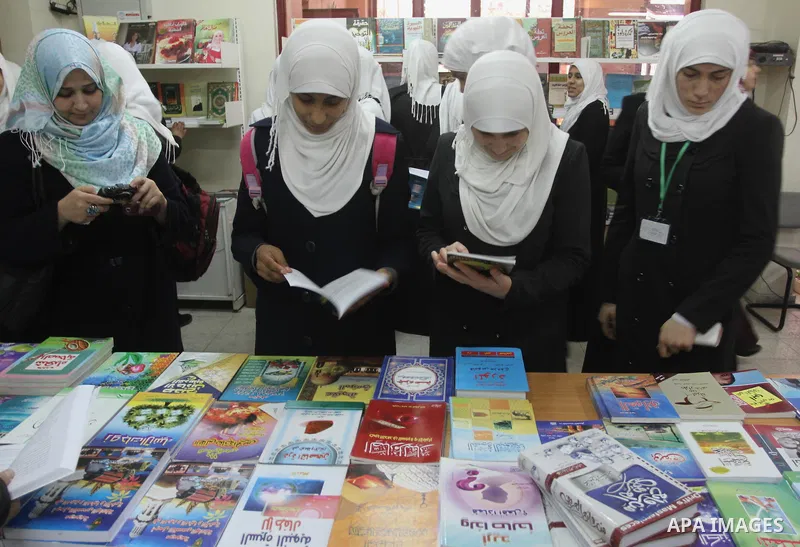 Palestinian students read books during the opening of an exhibition "Gaza Hashim" Book, in Gaza city , March 10, 2014. Photo by Mohammed Asad