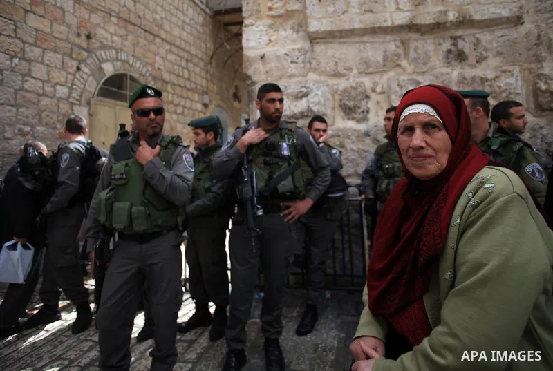 A Palestinian woman walks past Israeli policemen as they prevent Palestinians from entering the al-Aqsa mosque compound, in Jerusalem's Old City on March 11, 2014. Israeli authorities on Tuesday closed a number of Al-Aqs...