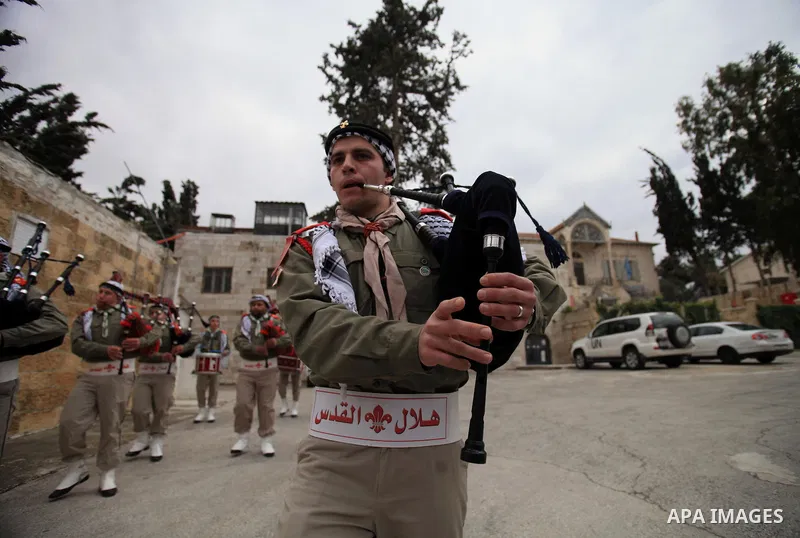 Palestinian scouts play musical instruments as they parade through the streets during a campaign the Spring shopping, in Jerusalem old city, on March 15, 2014. Photo by Saeed Qaq
