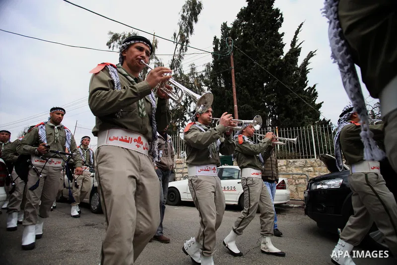 Palestinian scouts play musical instruments as they parade through the streets during a campaign the Spring shopping, in Jerusalem old city, on March 15, 2014. Photo by Saeed Qaq
