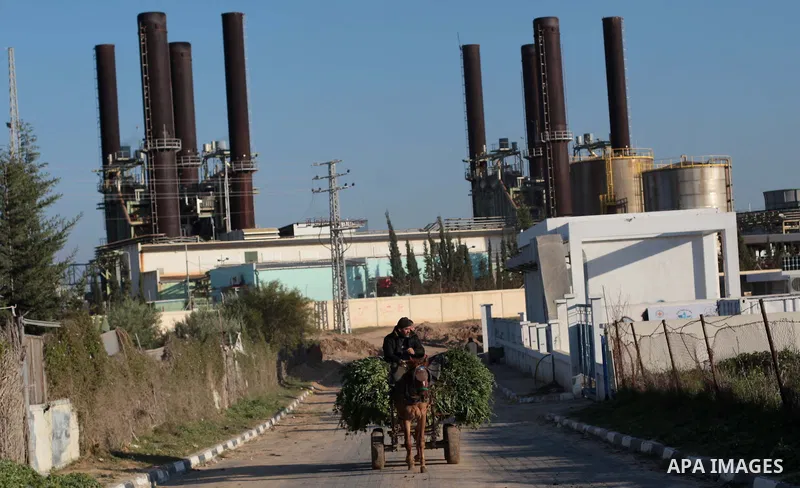 Palestinians walk past Gaza's power station in the Gaza Strip March 15, 2014. The Gaza Strip's sole power station stopped generating electricity on Saturday, causing blackouts throughout the territory after it ran out of...