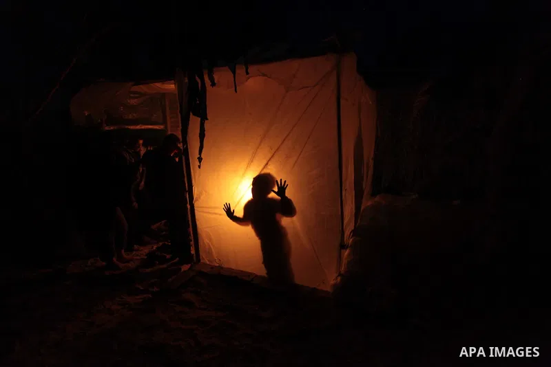A Palestinian family sits inside their makeshift house during power cuts in Khan Younis in the southern Gaza Strip March 15, 2014. The Gaza Strip's sole power station stopped generating electricity on Saturday, causing b...