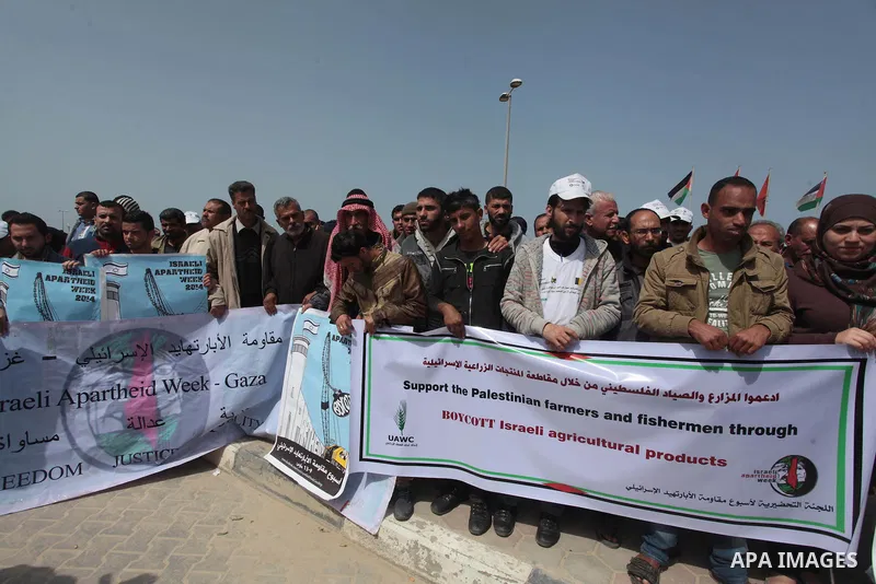 Palestinian fishermen hold banners in a protest to demand the boycott of the Israeli agricultural products, during the 10th annual Israeli Apartheid Week, at the seaport of Gaza City on March 16, 2014. Photo by Ashraf Am...