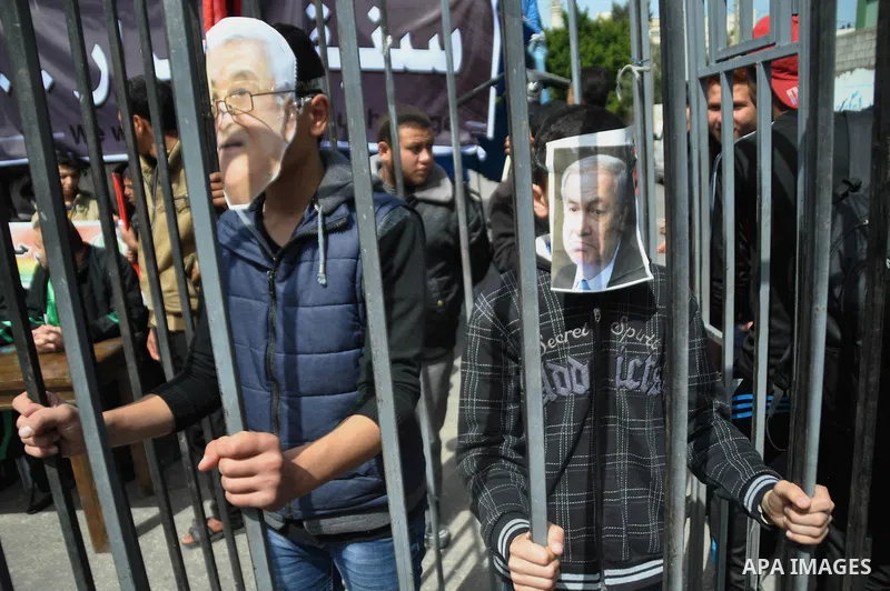 Protesters wearing a mask depicting Palestinian President Mahmoud Abbas and Israeli Prime Minister Benjamin Netanyahu during a protest against the Egyptian-Israeli blockade on Gaza Strip, in Gaza City on March 16, 2014....