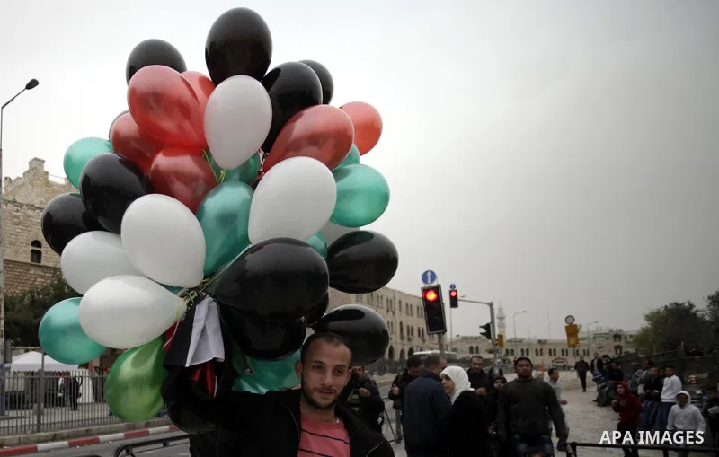 A Palestinian man hold up ballons with his national flag colors during a rally in Jerusalem's Old City on March 17, 2014, to show their support for Palestinian president Mahmud Abbas who is on an official visit to the US...
