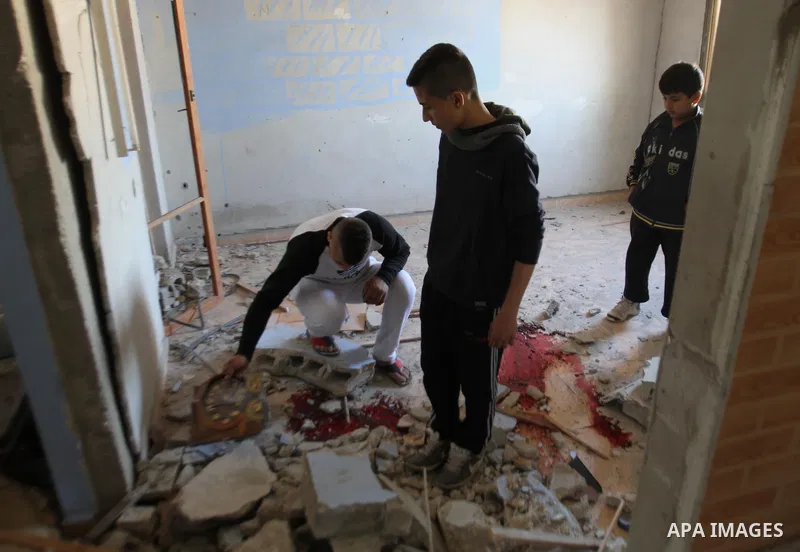 Palestinians look in a house filled with debris where Palestinian Hamas militant Hamza Abu Alhija was killed in the West Bank refugee camp of Jenin March 22, 2014. Israeli forces shot and killed four Palestinians on Satu...