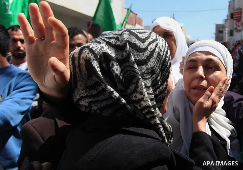 Palestinians mourn during the funeral of Hamza Abu Al-Heja, 20, a member of the military wing of Hamas, the Ezzedine al-Qassam Brigades in the northern West Bank city of Jenin on March 22, 2014 after he was killed alongs...