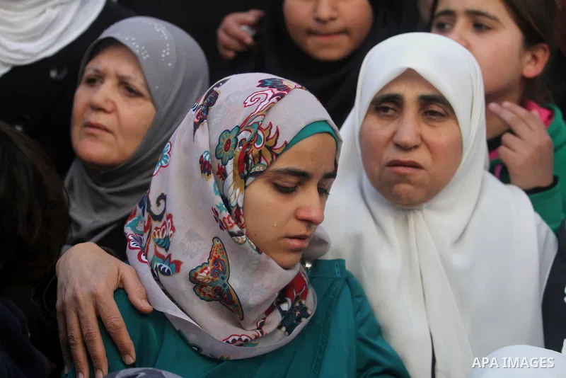 Palestinian women watch during the funeral of three Palestinians: Yazan Basim, Mahmoud Abu Zena and Hamza Abu Al-Haija, at Jenin Refugee Camp in Jenin, West Bank, 22 March 2014. Three Palestinians were killed and at leas...