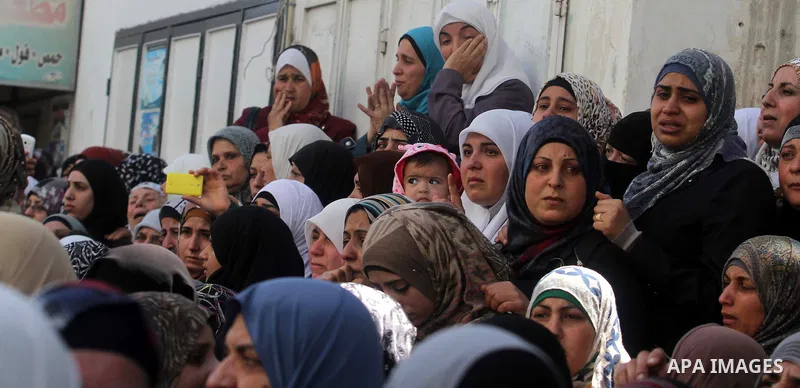 Palestinian women watch during the funeral of three Palestinians: Yazan Basim, Mahmoud Abu Zena and Hamza Abu Al-Haija, at Jenin Refugee Camp in Jenin, West Bank, 22 March 2014. Three Palestinians were killed and at leas...