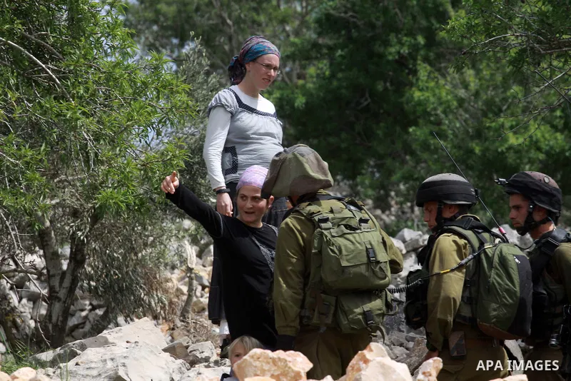 Israeli security forces stand guard in front of Jewish settlers in the West Bank village of Burin south of Nablus, March 23, 2014. Clashes broke out Sunday morning after Jewish settlers from the nearby Bracha settlement...