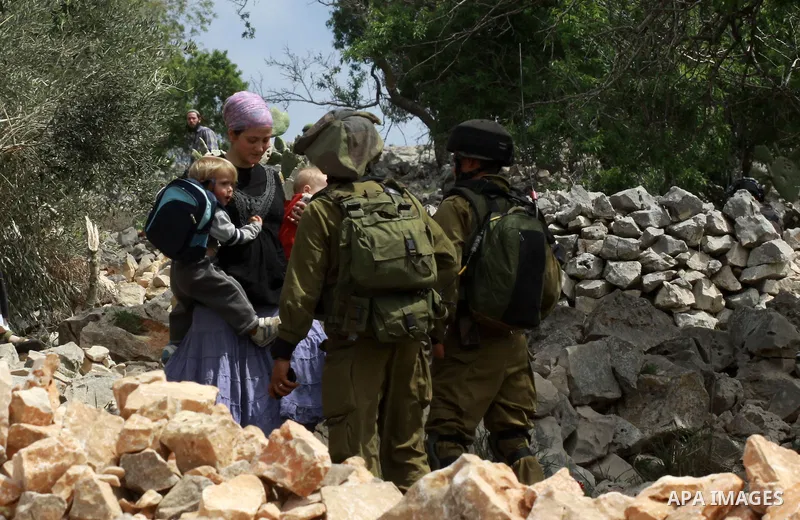 Israeli security forces stand guard in front of Jewish settlers in the West Bank village of Burin south of Nablus, March 23, 2014. Clashes broke out Sunday morning after Jewish settlers from the nearby Bracha settlement...
