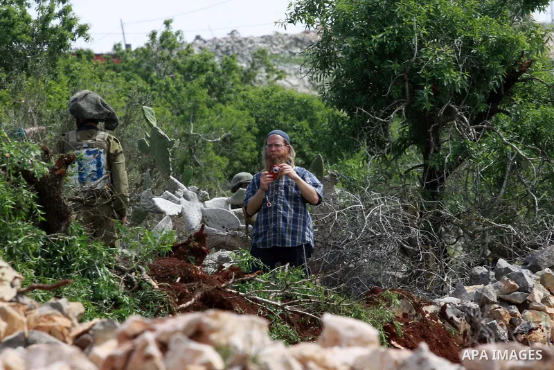 Israeli security forces stand guard in front of Jewish settlers in the West Bank village of Burin south of Nablus, March 23, 2014. Clashes broke out Sunday morning after Jewish settlers from the nearby Bracha settlement...