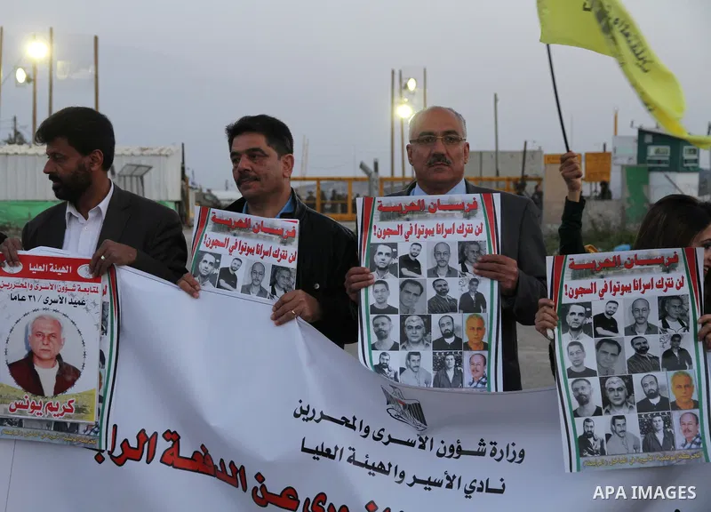 Palestinians hold pictures of detainees being held in Israeli prisons since before the 1993 Oslo peace accords as they protest against the postponement of the release of the prisoners outside the gates of Ofer prison, ne...