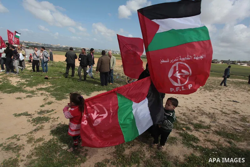 Palestinian supporters of the Popular Front for the Liberation of Palestine hold banner and national flags during a rally marking Land Day in Jabalya in the northern Gaza Strip on March 30, 2014. The annual demonstration...