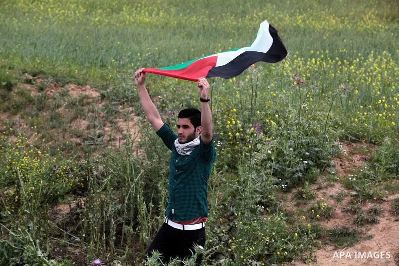 A Palestinian supporter of the Popular Front for the Liberation of Palestine holds a Palestine flag during a rally marking Land Day in Jabalya in the northern Gaza Strip on March 30, 2014. The annual demonstrations mark...