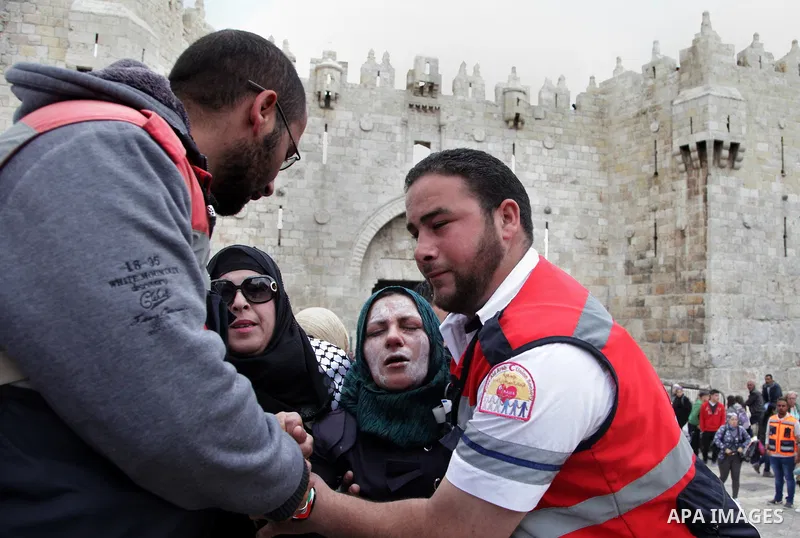 A Palestinian medic treats a woman after Israeli border police officers sprayed pepper spray during a demonstration marking the Land Day in Jerusalem's old city, Sunday, March 30, 2014. The Land Day commemorates the Isra...