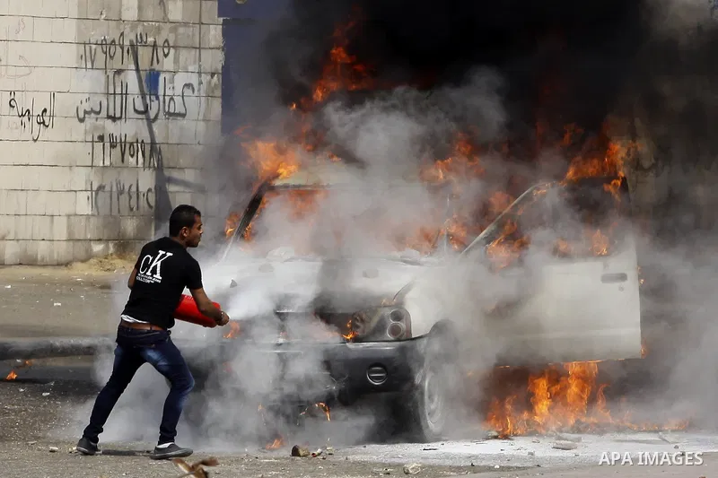 An Egyptian man tries to extinguish a police car set on fire by students of Al-Azhar University, who are supporters of the Muslim Brotherhood and deposed President Mohamed Mursi, during clashes with riot police at the un...