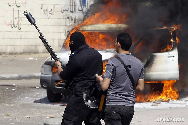An egyptian riot policeman takes position in front of a police car set on fire by students of Al-Azhar University during clashes with supporters of the Muslim Brotherhood and deposed President Mohamed Mursi at University...