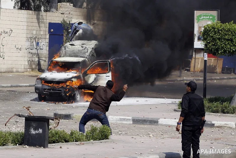Riot police take their positions in front of a police car set on fire by students of Al-Azhar University during clashes with supporters of the Muslim Brotherhood and deposed President Mohamed Mursi at University's campus...