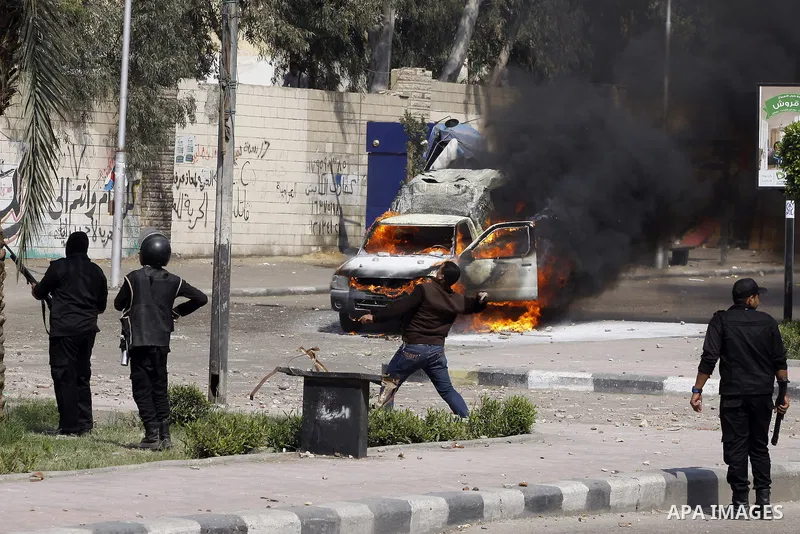 Riot police take their positions in front of a police car set on fire by students of Al-Azhar University during clashes with supporters of the Muslim Brotherhood and deposed President Mohamed Mursi at University's campus...