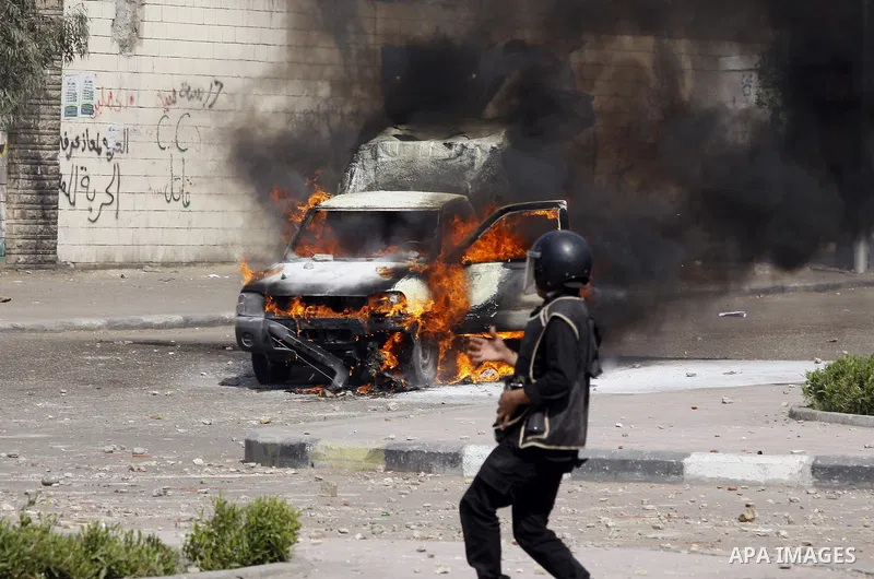 Riot police take their positions in front of a police car set on fire by students of Al-Azhar University during clashes with supporters of the Muslim Brotherhood and deposed President Mohamed Mursi at University's campus...