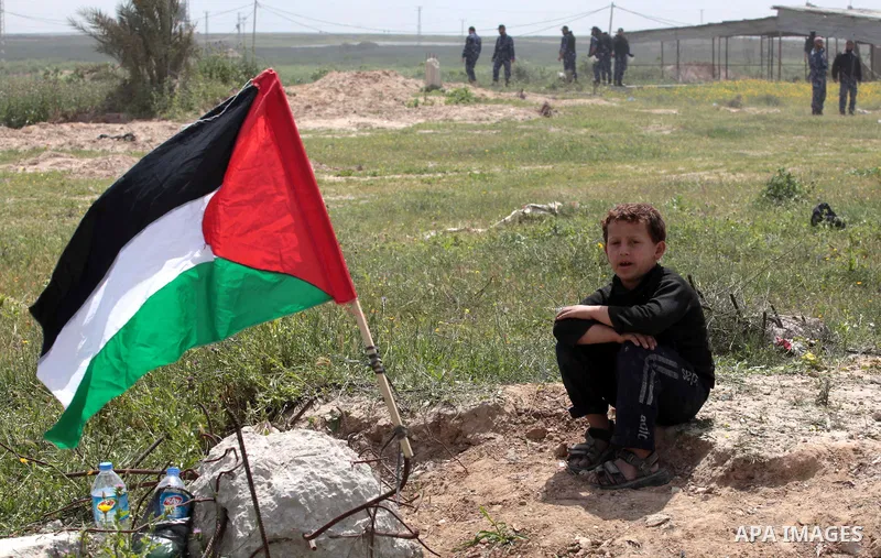 A protester waves a Palestinian flag towards the Israeli border during a protest marking Land Day at the border between Israel and Gaza Strip, on March 30, 2014. March 30 marks Land Day, the annual commemoration of prote...