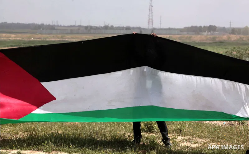A protester waves a Palestinian flag towards the Israeli border during a protest marking Land Day at the border between Israel and Gaza Strip, on March 30, 2014. March 30 marks Land Day, the annual commemoration of prote...