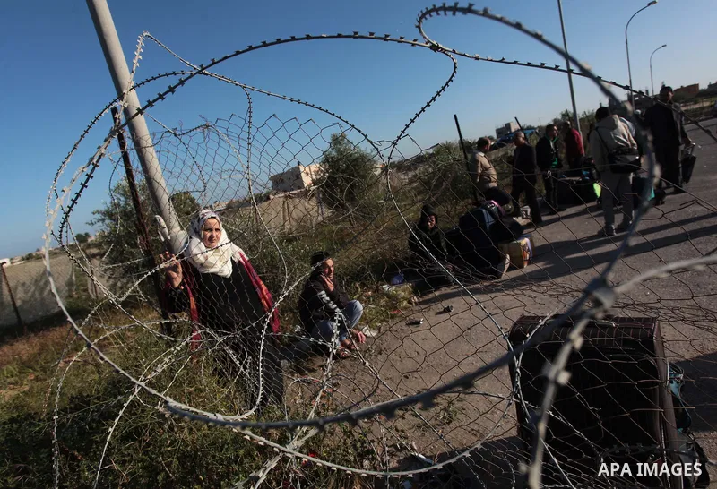 Palestinians hoping to cross into Egypt wait behind a barbed wire fence at the Rafah crossing between Egypt and the southern Gaza Strip March 31, 2014. Egyptian authorities partially reopened Rafah border crossing, Gaza'...