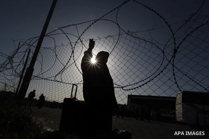 A Palestinian woman hoping to cross into Egypt waits behind a barbed wire fence at the Rafah crossing between Egypt and the southern Gaza Strip March 31, 2014. Egyptian authorities partially reopened Rafah border crossin...