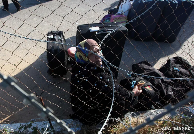 A Palestinian woman hoping to cross into Egypt waits behind a barbed wire fence at the Rafah crossing between Egypt and the southern Gaza Strip March 31, 2014. Egyptian authorities partially reopened Rafah border crossin...