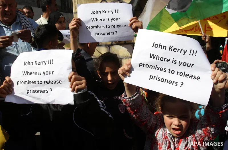 Palestinian children hold placards during a protest demanding the U.S. Secretary of State John Kerry to work for release Palestinian prisoners in Israeli jails, at Balata refugee camp near the West Bank city of Nablus, M...