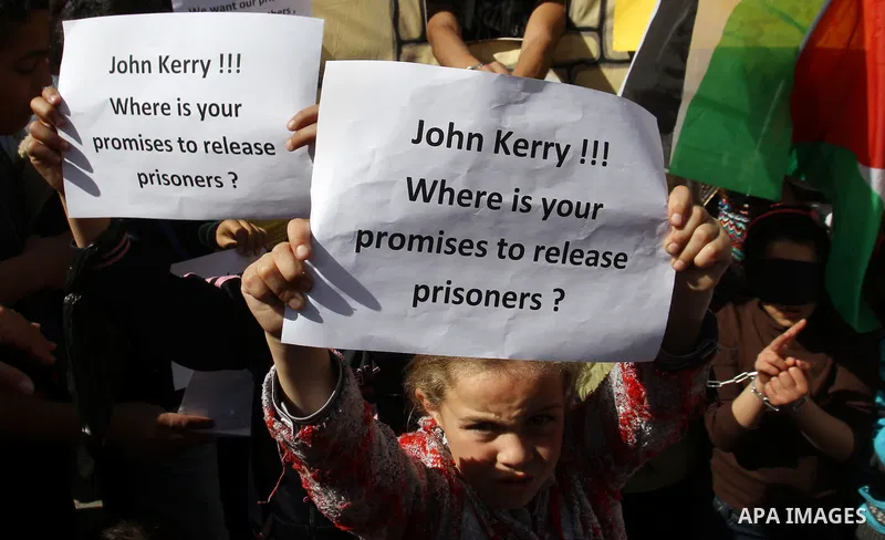 Palestinian children hold placards during a protest demanding the U.S. Secretary of State John Kerry to work for release Palestinian prisoners in Israeli jails, at Balata refugee camp near the West Bank city of Nablus, M...