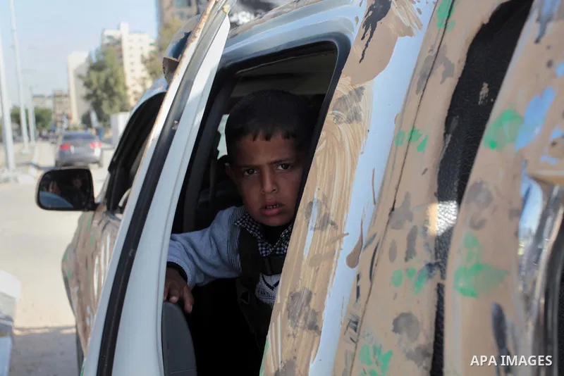 A Palestinian boy looks on as militants of Al-Nasser brigades, the military wing of the Popular Resistance Committees, march with weapons during an anti-Israeli protest in Gaza City March 31, 2014. Photo by Ashraf Amra