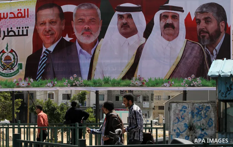 Palestinians walk past a mural depicting of the Palestinian Hamas leader Khaled Meshaal, the former Emir of Qatar Sheikh Hamad bin Khalifa Al Than, Emir of Qatar Tamim Bin Hamad, Palestinian Prime Minister in Gaza Strip...