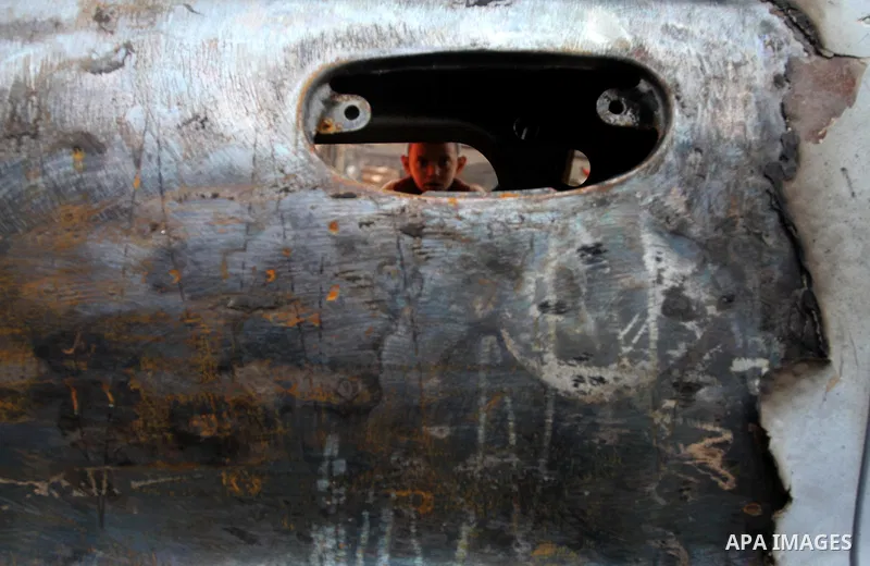 A Palestinian boy looks through a burnt out car window following an overnight Israeli air strike on Jabalia in the northern Gaza Strip, on April 4, 2014. After Israel called off the planned release of 26 Palestinian pris...