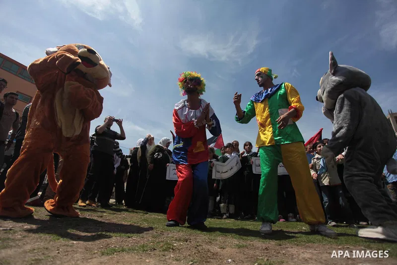 Palestinian clowns play with children in a rally marking the Children's Day during a protest against Israeli blockade on Gaza strip in Gaza city, on April 05, 2014. Photo by Ashraf Amra