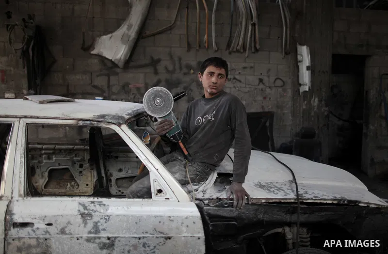 Twelve-year-old Palestinian boy Saher Totah works in a car workshop in Gaza City on April 7, 2014. There are about 65,000 working children in the Palestinian territories, accounting for 6% of all children at 5-14, accord...