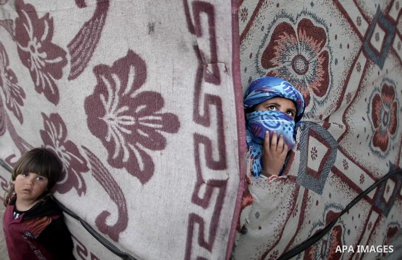 A Palestinian girl poses for a picture behind a curtain as she plays in front of her family's house at poverty-stricken quarter of Zaytoon neighborhood, in Gaza City on April 07, 2014. Photo by Ezz Zanoun