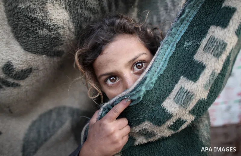 A Palestinian girl poses for a picture behind a curtain as she plays in front of her family's house at poverty-stricken quarter of Zaytoon neighborhood, in Gaza City on April 07, 2014. Photo by Ezz Zanoun