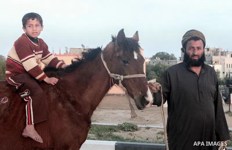 A Palestinian man walks with his son as he rides a horse at poverty-stricken quarter of Zaytoon neighborhood, in Gaza City on April 07, 2014. Photo by Ezz Zanoun