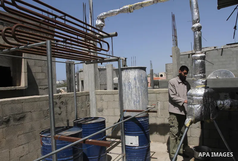 Palestinian Mahmoud Soboh, 28, works on a machine to extract fuel from plastic at a workshop in his house in Nuseirat refugee camp, central Gaza Strip, April 9, 2014. Soboh succeeded in production of fuel oil by the ther...