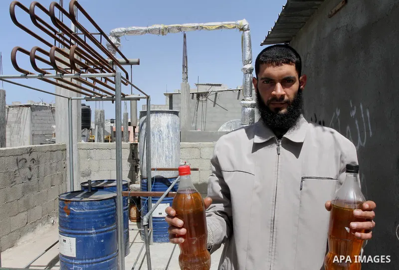 Palestinian Mahmoud Soboh, 28, displays fuel oil extracted from plastic at a workshop in his house in Nuseirat refugee camp, central Gaza Strip, April 9, 2014. Soboh succeeded in production of fuel oil by the thermal ana...