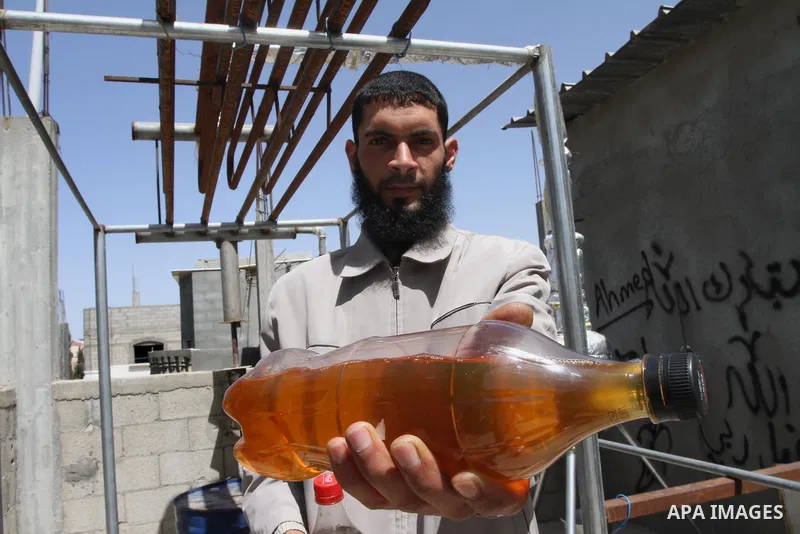 Palestinian Mahmoud Soboh, 28, displays fuel oil extracted from plastic at a workshop in his house in Nuseirat refugee camp, central Gaza Strip, April 9, 2014. Soboh succeeded in production of fuel oil by the thermal ana...