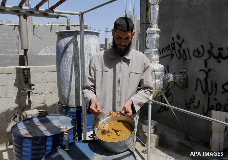 Palestinian Mahmoud Soboh, 28, displays grease oil extracted from plastic at a workshop in his house in Nuseirat refugee camp, central Gaza Strip, April 9, 2014. Soboh succeeded in production of fuel oil by the thermal a...
