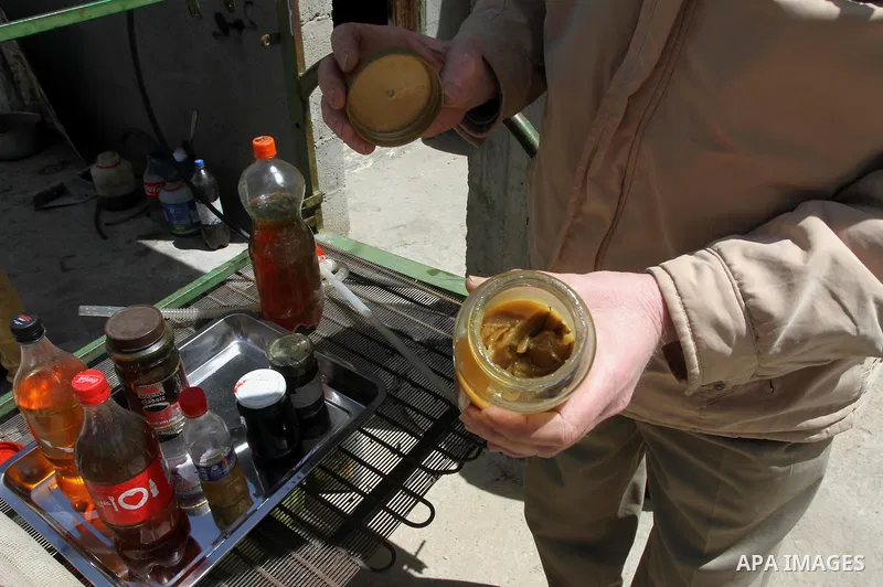 Palestinian Ibrahim Sobo, displays grease oil extracted from plastic at a workshop in his house in Nuseirat refugee camp, central Gaza Strip, April 9, 2014. Soboh succeeded in production of fuel oil by the thermal analys...