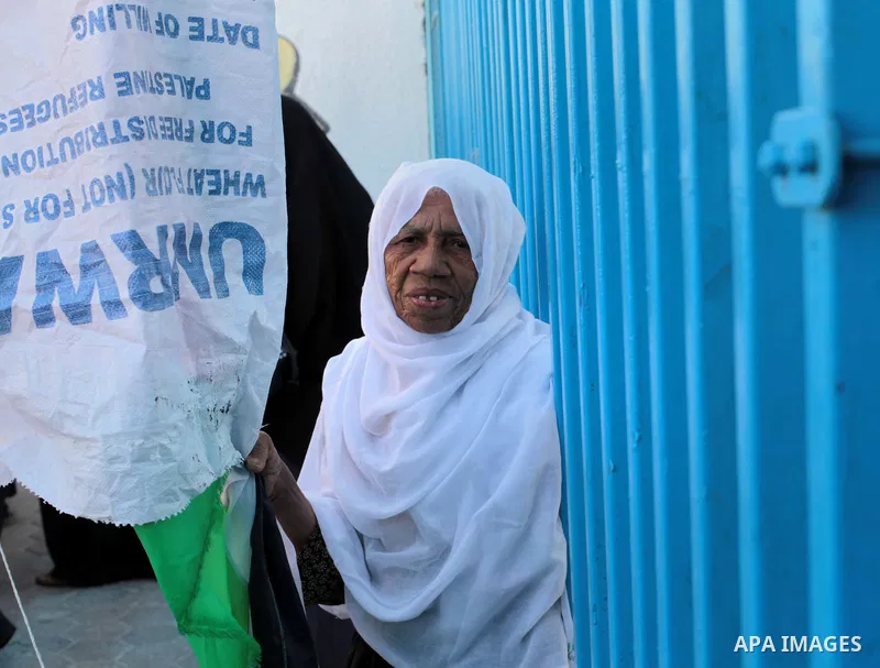A Palestinian woman holds a sack of flour during a protest a the decision made by the United Nations Relief and Works Agency (UNRWA) to reduce food aid delivered to the Gaza Strip in front of the UNRWA headquarters in Ga...